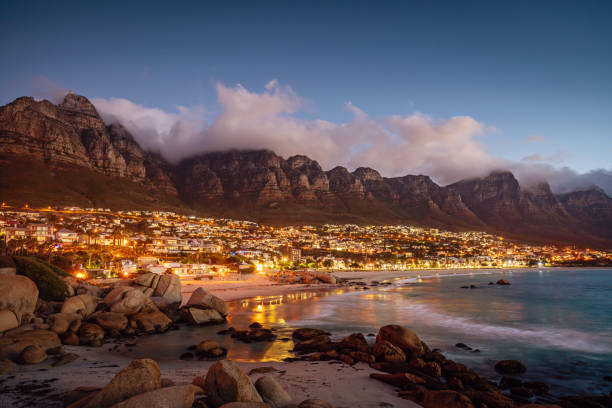 Beautiful illuminated Camps Bay, Scenic view after sunset with beautiful cloudscape. Camps Bay, famous suburb of the city of Cape Town with white sandy beaches underneath the Table Mountain. Cape Town, South Africa